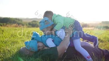 快乐的年轻<strong>父亲</strong>和他的<strong>孩子</strong>躺在公园的草坪上。 三个快乐的<strong>孩子</strong>和他们的<strong>父亲</strong>一起玩。 儿童
