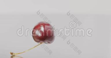 一个成熟的红色大樱桃的特写慢慢落下，填满屏幕。 慢动作。 浆果背景。 全高清视频
