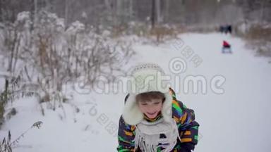 冬天，一个非常可爱快乐的小男孩在公园里跑步。 冬天的时候。 快乐的男孩在雪地冬季公园玩得很开心。 他是