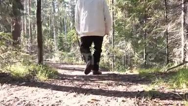 穿着风衣和裤子的人为了凉爽的天气。 录像。 旅行者在露天的树林里散步
