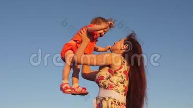 妈妈把女儿扔到天上。 母亲和一个小孩子在蓝天上玩耍。 幸福的家庭在玩耍