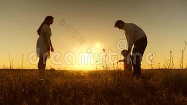 年轻漂亮的家庭在田野里和孩子在夕阳下，一个小孩子学会和<strong>爸爸妈妈</strong>一起散步，慢动作