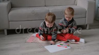 两个双胞胎兄弟蹒跚学步的孩子一起画坐在地板上的标记。