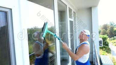 白人英俊男子，清洁服务工人，穿着蓝色工作服，戴着一顶帽子，擦擦，擦窗户