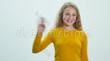 一个女孩站在<strong>演播室</strong>的白色背景上挥舞着她的手
