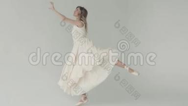优雅的年轻芭蕾舞演员穿着尖角鞋和一件轻飘飘的连衣裙。 白色背景的芭蕾舞演员。 慢动作