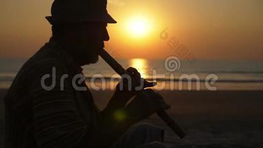 日落时分在沙滩上吹<strong>竹笛</strong>的老人剪影