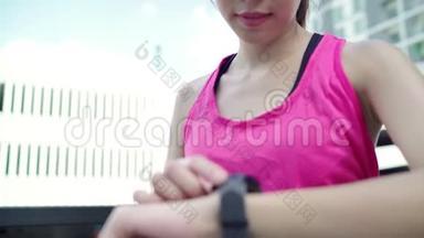 健康美丽的年轻亚洲运动员妇女设置和检查进展，看心率监测在智能手表运行。