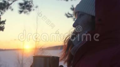 这位女游客正在日落时分在白雪皑皑的冬林里<strong>喝热水</strong>瓶里的茶
