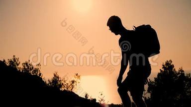 日落时，一个背着背包的人上升到山顶。 日落时那个人的剪影。 健康活动