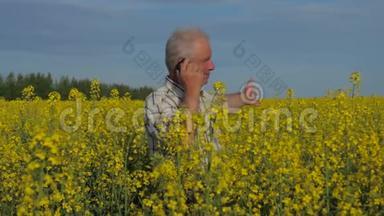 一个农民站在一片盛开的黄色<strong>油菜花田</strong>里，打电话。