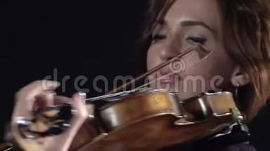 女孩在小提琴的琴弦上<strong>鞠躬</strong>。 黑色背景。 关门