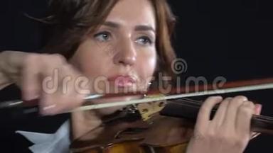 女人在小提琴的弦上<strong>鞠躬</strong>。 黑色背景。 关门