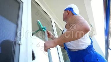 白人英俊男子，清洁服务工人，穿着蓝色工作服，戴着一顶帽子，擦擦，擦窗户