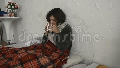 生病的女人躺在床上，穿着毛衣，喝着热饮料