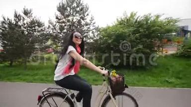 骑自行车的快乐年轻女人的肖像。 她的自行车篮子里有花和一个包。 她喜欢这次旅行。