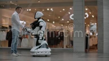 一个男人和机器人机器人站在一起，问他问题，并通过点击机器人身体上的屏幕来寻求帮助。