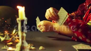 一个年轻的吉普赛人穿着红色的衣服在烛光下的桌子上，用算命的卡片来读未来。 平均计划