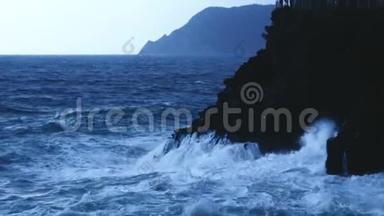 蓝色的海水波浪撞击岩石悬崖形成泡沫，暴风雨天气