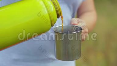 女人把热水瓶里的茶倒进杯子里。