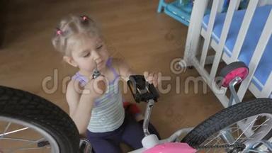 一个小女孩，用螺丝刀坐在托儿所里自修自行车。