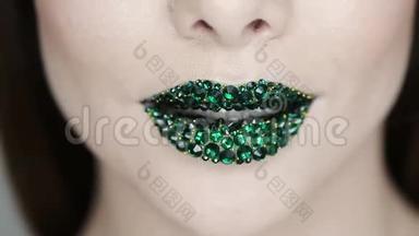 绿色的嘴唇覆盖着莱茵石。 绿色口红的漂亮女人。