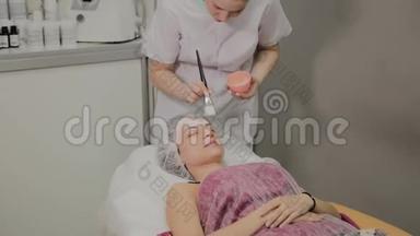 熟练的美容师在室内水疗沙龙里给躺着的女人戴上面具。