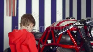 小可爱的男孩坐在<strong>红</strong>色的大摩托车上。 这个小男孩在演播室里以美<strong>国风</strong>格微笑。 关闭