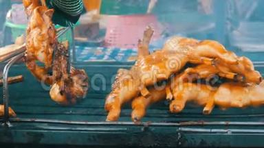 全鸡胴体烤架串在木棒上烤在烤架上。 泰国街头美食。 男人`双手翻身