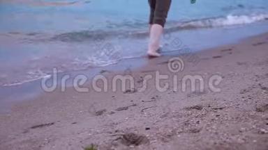 在日落时分，赤脚沿着沙滩上的<strong>海浪</strong>走近。沿着海滩和<strong>海浪</strong>散步的女人的腿