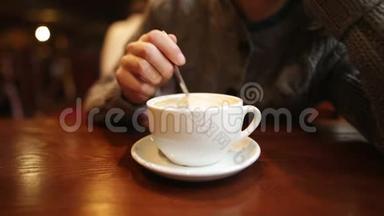 一个沮丧的年轻不耐烦的女孩在一个白色的杯子里搅动糖。 疲惫的女人在等男朋友，她很无聊。
