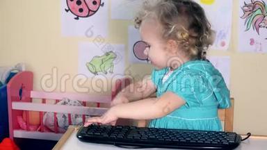 情绪化的学步女孩在她的小桌子上玩电脑键盘