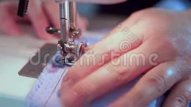 裁缝的手降低了缝纫机的针头。 她开始缝衣服