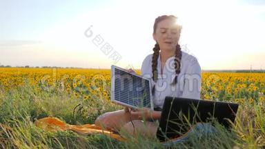太阳能，女孩手里拿着太阳花领域的太阳能电池，年轻女子用太阳能电池板为笔记本电脑<strong>供电</strong>