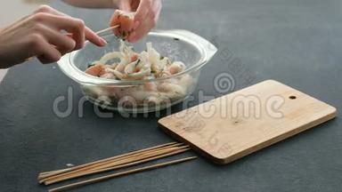 特写女人`她的手煮腌制的什锦或什锦串，鸡肉在木串和洋葱在木板上