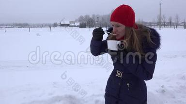 戴红帽的女人在寒冷的冬天在户外吃<strong>热汤</strong>。 4K