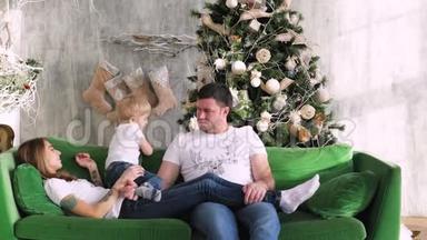 一家人聚集在圣诞树周围。 在沙发上玩。 圣诞节室内