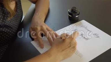 一位年轻女子用刻字技巧在纸上书写书法的特写镜头。 她写着梦想远大的目标