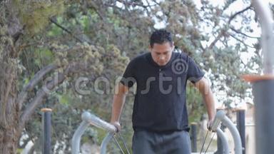 街头训练。 西班牙裔男子在公园的健身<strong>室外</strong>健身房做平行<strong>酒吧</strong>蘸阻力带。