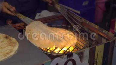 泰国一家夜市在明火上烹制异国情调的泰国煎饼的过程。 泰国菜的概念。 亚洲食物