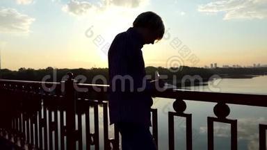 才华横溢的人站着，把他的想法写在夕阳西下的一座桥上