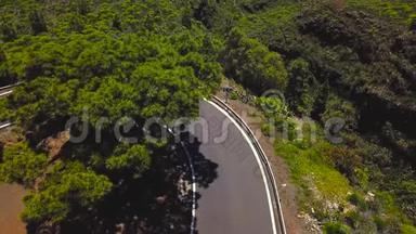 在西班牙加那利群岛的特内里费，一辆汽车和骑自行车的人沿着一条山路行驶的俯视图。 去泰德火山的路