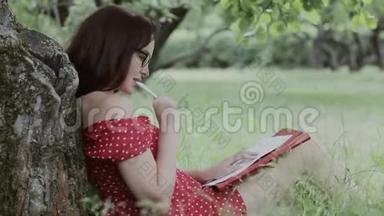 小女孩坐在树下的草地上写笔记