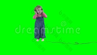 可爱的<strong>小女孩</strong>带着大耳机在绿色背景下<strong>跳舞</strong>