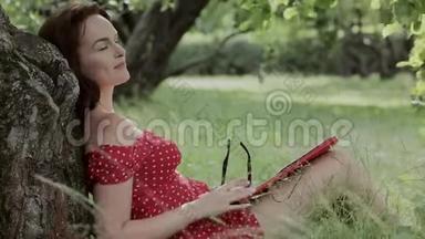 小女孩坐在树下的草地上写笔记