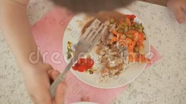在幼儿园吃午饭.. 一个孩子正在吃一个配菜，配菜是盘子里的蔬菜。 一个孩子的手`特写。