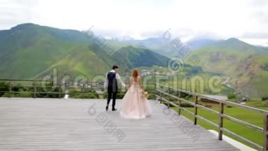 新婚快乐的新婚夫妇在他们的婚礼上，在群山的背景下。 结婚照会。 格鲁吉亚