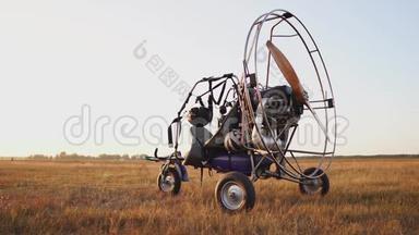 汽车<strong>滑翔伞</strong>在日落时分用木制螺旋桨站在田野里，飞行员伸出降落<strong>伞</strong>，