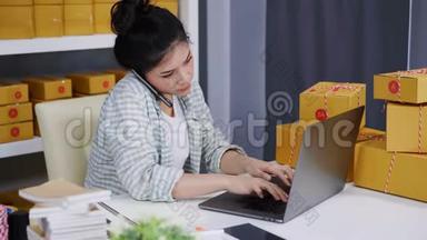 女人在智能手机上讲话，用电脑手提电脑从家庭办公室在线销售产品