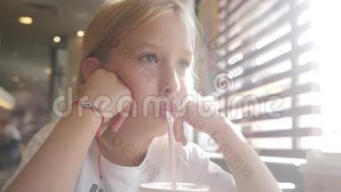 小女孩在咖啡馆喝牛奶鸡尾酒可可加牛奶。 孩子喝奶昔坐在咖啡馆里。